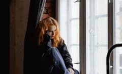 A woman sitting quietly beside a window.